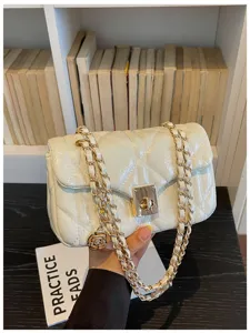 Detailed view of a white quilted oil-skin flap bag with a golden chain strap and rose charm.