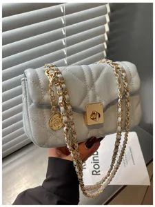 Close-up of light blue oil-skin quilted crossbody bag with gold chain and rose charm