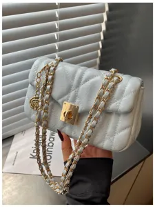 Detail shot of light blue quilted leather bag featuring a gold chain and charm