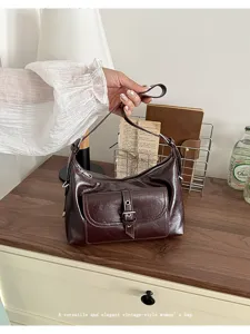 Close-up view of a stylish vintage dark brown oil wax leather shoulder bag with buckle