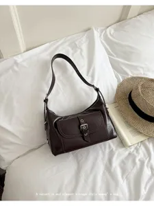 Vintage brown oil wax leather underarm bag with buckle pocket on white bedding