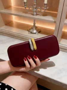Elegante pochette da sera bordeaux con esclusivi anelli intrecciati gialli e grigi