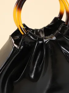Gros plan d'un sac en similicuir plissé noir avec des poignées en acrylique ambré