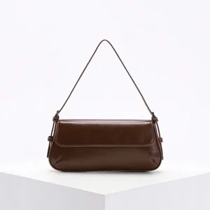Minimalistische burgunderrote Baguette-Schultertasche auf einem weißen geometrischen Sockel