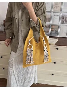Detaillierte Nahaufnahme der gelben Stricktasche mit Evil Eye Quasten und Anhängern
