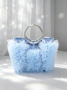 Close-up of a sweet light blue handbag with delicate tulle ruffles and metal ring handles.