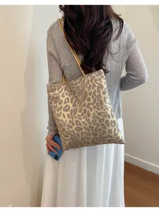 Detail shot of a leopard print sequin tote bag carried over the shoulder by a woman