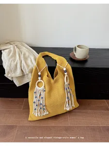 Detailaufnahme einer gelben Stricktasche für den Strand mit Holzringen und Quasten.