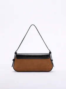 Zweifarbige Baguette-Tasche aus braunem Wildleder und schwarzem Leder vor weißem Hintergrund