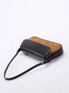 Nahaufnahme einer zweifarbigen Baguette-Tasche aus schwarzem Leder und braunem Wildleder