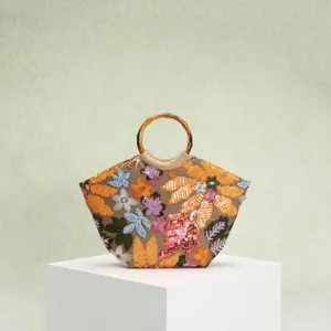 Detailansicht einer eleganten Strandtasche mit Blumenstickerei und Bambusgriffen