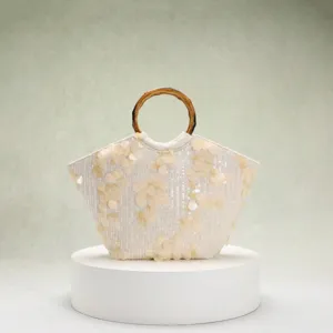 Detailansicht der cremefarbenen Strandtasche mit 3D-Blumenpailletten und Bambusgriff
