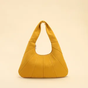 Gros plan d'un sac hobo croissant jaune avec des coutures matelassées au design unique.