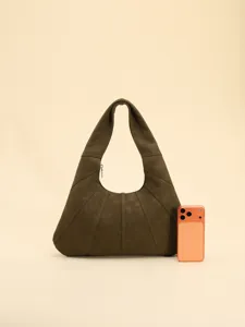 Gros plan d'un sac hobo vintage avec coutures texturées à côté d'un téléphone pour l'échelle