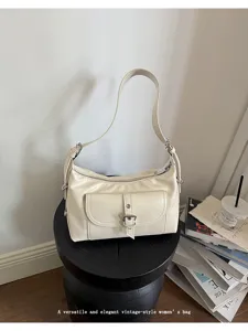 Detailed view of vintage-style cream oil wax leather shoulder bag on a minimalist stool