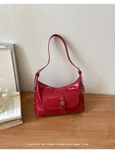 Close-up view of a red vintage-style oil wax leather shoulder bag featuring a front pocket