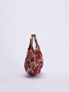 Gedetailleerde close-up van de rode vintage stoffen handtas met unieke bamboe handvatten.