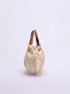 Gedetailleerd overzicht van de geplooide stoffen handtas met natuurlijke bamboe handvatten.