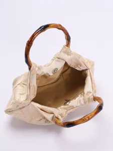 Detailweergave van de elegante vintage stoffen handtas met bamboe handvatten en geplooid ontwerp.