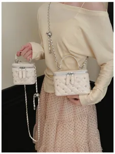Detailed view of elegant quilted beige vanity bags with rhinestones and chain straps