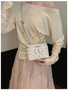 Close-up view of an elegant cream quilted box bag with crystal and pearl embellishments