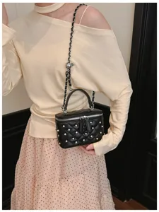 Close-up of black quilted box bag with pearl embellishments and chain strap