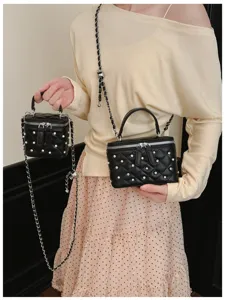 Detailed shot of two sizes of black quilted box bags with pearl and rhinestone decor.
