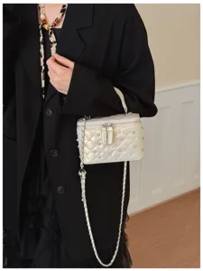 Elegant white quilted box vanity bag with pearls and chain strap worn on model