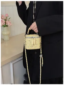 Close-up of a small yellow quilted vanity box bag with pearls and rhinestone embellishments