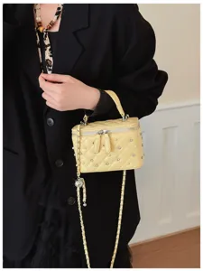 Detail view of elegant yellow quilted vanity box bag with pearls and rhinestones