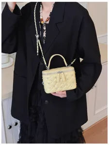 Model wearing a stylish yellow quilted box bag with pearl studs and silver chain strap