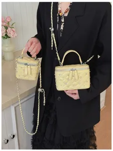 Detailed shot of two yellow quilted mini box bags with rhinestones and elegant chain straps