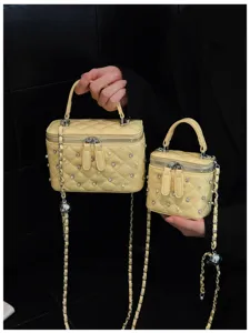 Detail view of yellow quilted box bags with pearls and rhinestones decoration and silver chains.