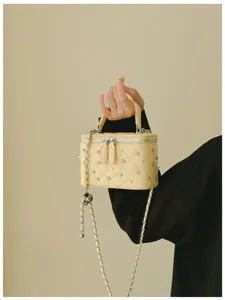 Close-up of cream quilted vanity bag featuring elegant pearl and rhinestone details