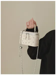 Detail view of quilted vanity bag with pearl and rhinestone embellishments and chain strap