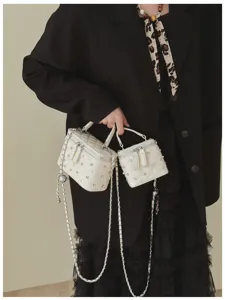 Detailed close-up of white quilted mini box bags with pearls and rhinestones decoration