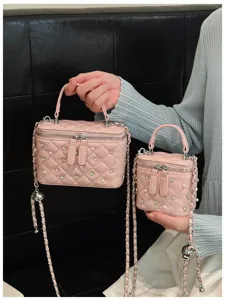 Close-up detail showing two pink quilted vanity bags with pearls and chain straps.