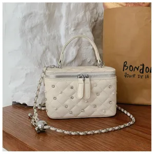 Detailed view of cream quilted vanity bag adorned with pearls and shimmering rhinestones