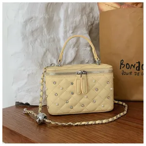 Detailed view of pale yellow quilted box bag with pearls and rhinestones