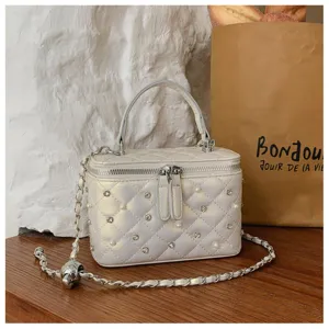 Close-up of quilted vanity bag with pearl and crystal embellishments and chain strap