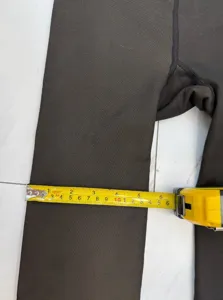 Detail shot measuring the leg width of black thermal translucent leggings with a tape measure.