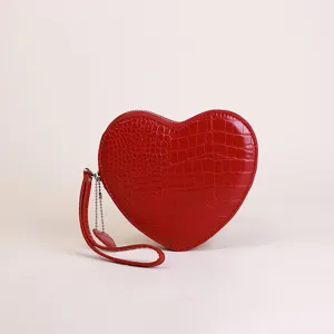 Close-up of a red heart-shaped wristlet with crocodile pattern and heart charm.