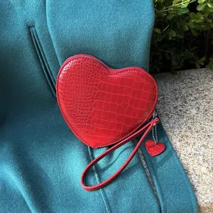 Close-up of red heart-shaped wristlet with crocodile texture and matching pendant