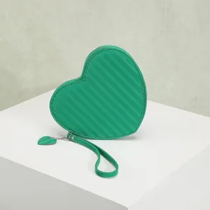 Detailed view of the green heart-shaped coin purse with striped pattern and charm.