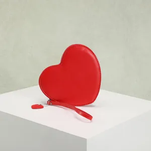 Detail view of red heart-shaped coin purse with matching wrist strap and heart charm.