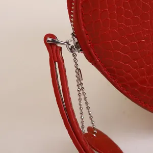 Detail close-up of red heart-shaped coin purse with crocodile texture and silver zipper
