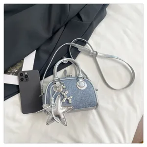 Detail view of the denim patchwork bowling bag featuring a silver star and balloon dog charm