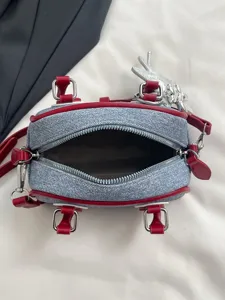 Small denim bowling bag featuring red contrast trim shown with an open top zipper