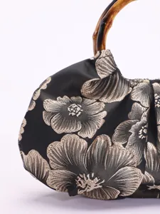 Detailopname van de vintage handtas met bamboe handvat gemaakt van zwarte brokaatstof.