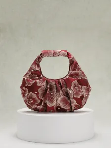 Primo piano di un'elegante borsa a mano plissettata in jacquard rosso con perle fini